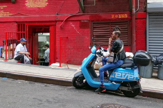 a woman on a Revel scooter parked outside a restaurant